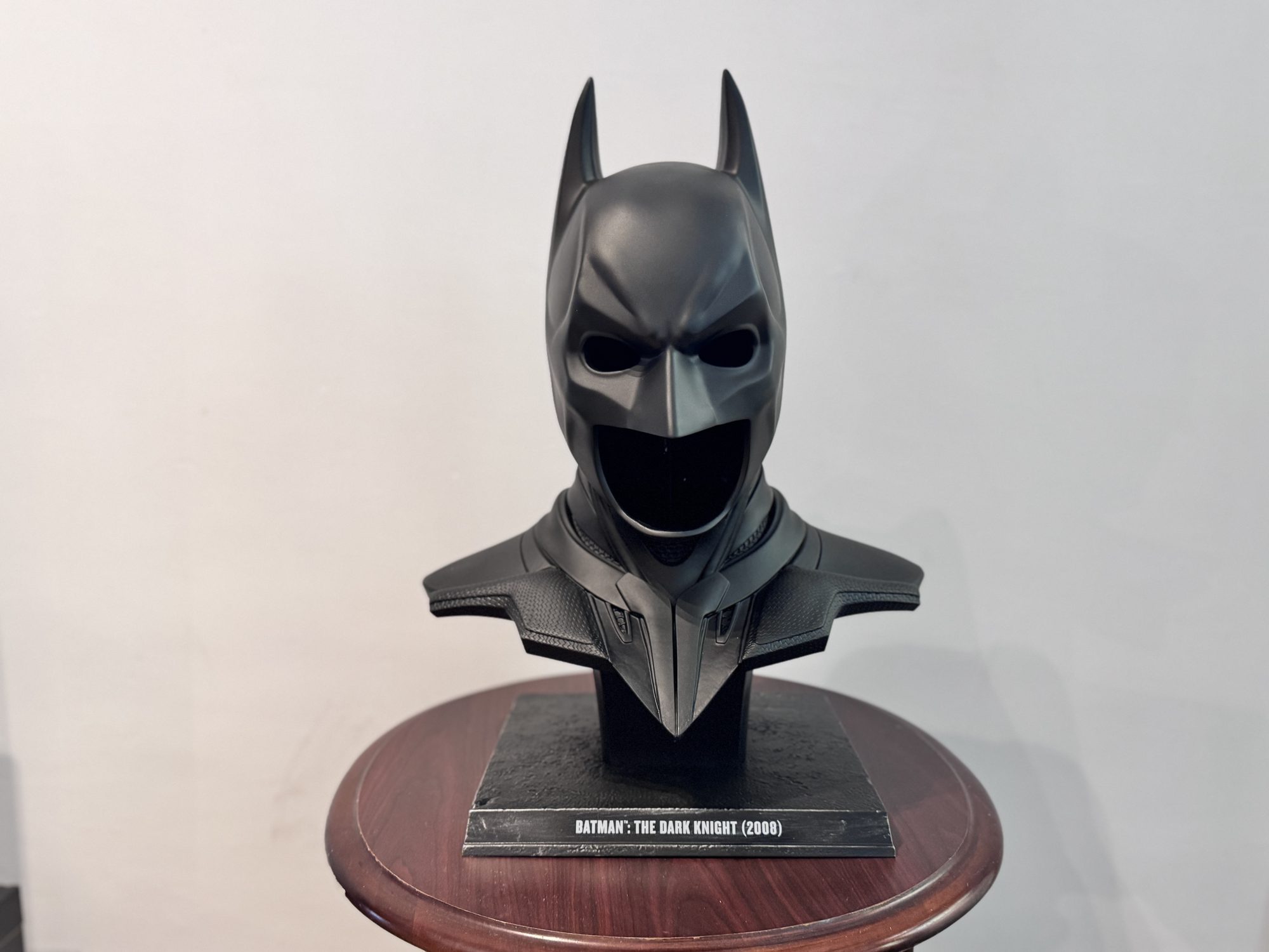 Batman cowl from The Dark Knight displayed on a plinth in the Gotham living room