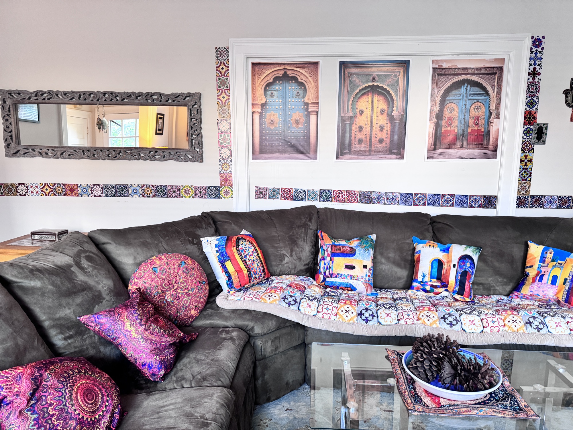 Icosium's living room: a deep corner sofa piled with embroidered cushions, under three framed prints of Moorish doorways and a band of patterned tile.