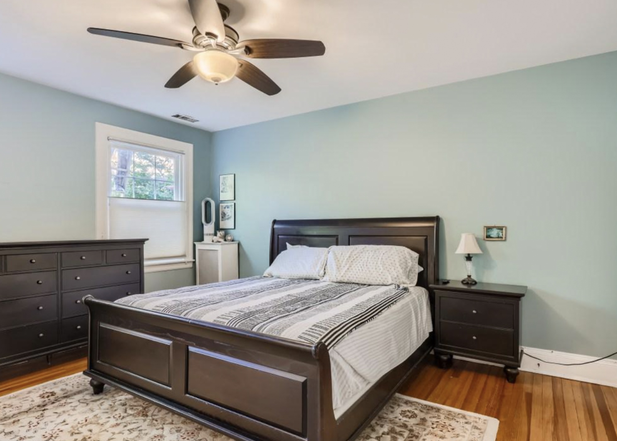 The Casablanca suite at Icosium: a dark wooden bed and matching dresser against a pale green wall, lit by a window and a ceiling fan.