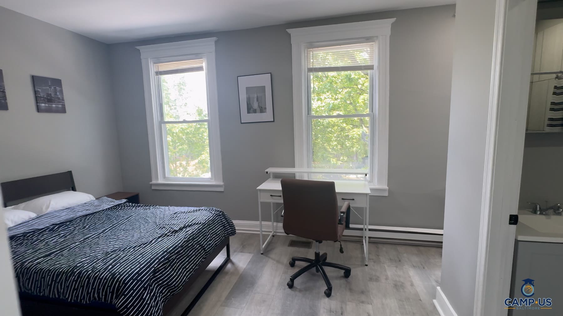 The New York room at Mohica: a bed and a desk against a whitewashed brick wall, lit by two windows, with the en-suite door at the side.