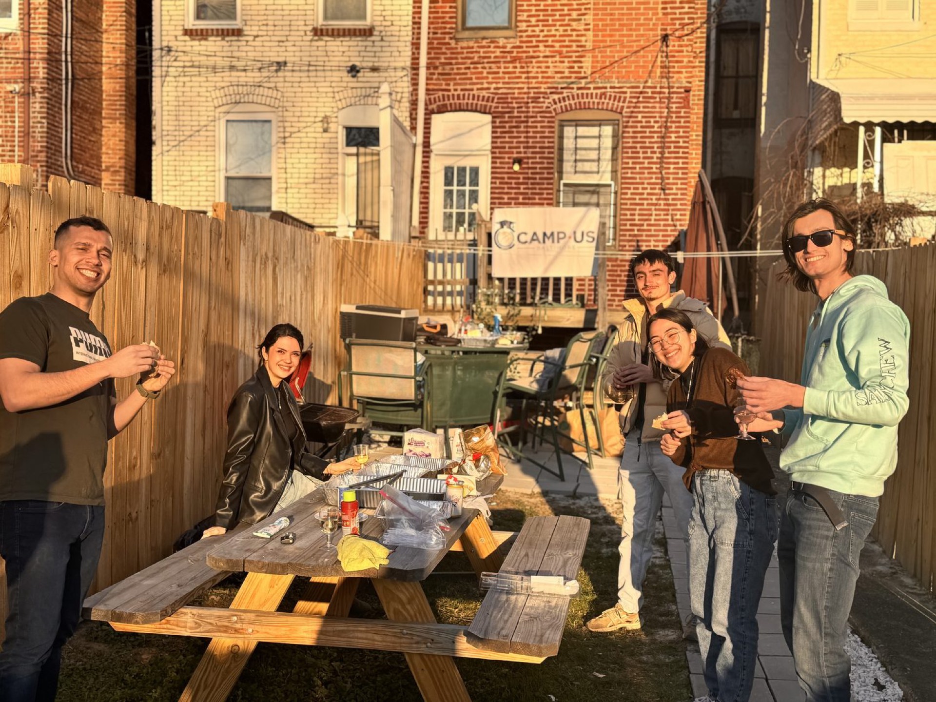 Residents at a CAMP-US backyard cookout, golden hour, Charles Village